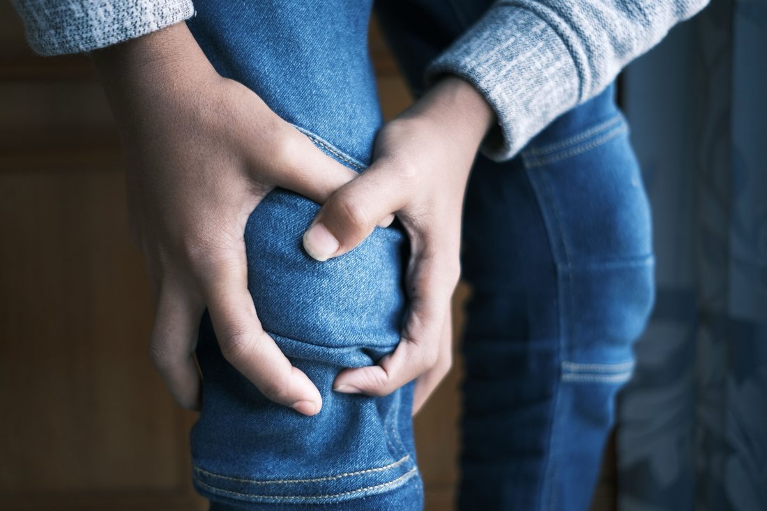 Mani strette attorno al ginocchio dolorante